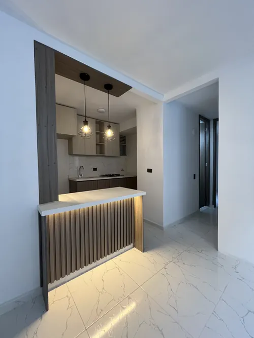 Cocina integral con barra iluminada en un apartamento remodelado por Droda